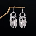 Bohemian feather tassel earrings in silver finish hanging on a natural wooden branch - Round Hollow Feather Tassel Style (E4602-2)