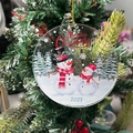 Macro shot of 2023 acrylic snowman Christmas ornament hanging on a festive tree branch - Snowman