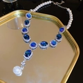 Detailed close-up of a blue gemstone necklace with pearls on a golden mirror tray - 57# Necklace Rhinestone Oval Glass Pearl Tassel