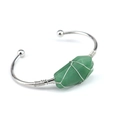 Close-up of silver copper wire wrapped green raw crystal on a polished open cuff bracelet - Green Aventurine