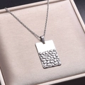 Dettaglio macro di un ciondolo rettangolare argento con finitura martellata e lucida - Collana Argento