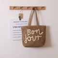 Brown woven straw tote bag featuring white embroidered Bonjour lettering for beach holidays - Coffee + Beige