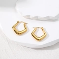Detailed macro view of gold geometric rhombus hoop earrings on white stone pedestals - Pentagon