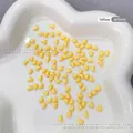 Detailed macro shot of yellow heart resin nail charms sized 4x5mm on a tray - 100 Pieces Set / Yellow