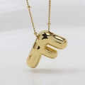 Macro shot of gold bubble letter F pendant with polished glossy mirror finish - Letter F (Necklace)