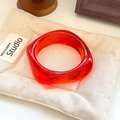 Macro shot of a red transparent resin wide cuff bracelet on a beige linen mat - Geometric Rhombus / Inner Diameter 65mm / Transparent Red