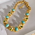 Detail van vintage gouden ketting met turquoise, groene edelstenen en parels op grijs papier - Vintage Goudkleurige Ketting met Turquoise Parels / Goud-Blauw