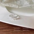 Dettaglio macro di un anello a fiocco in argento con zirconi su un piatto bianco - Colore Argento 929 / Aperto Regolabile / Argento