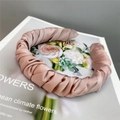 Detail view of pink pleated satin headband resting on a floral vintage magazine page - Orange Pink