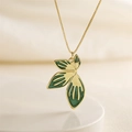 Golden necklace with green enamel petal pendant and detailed leaf veins on light fabric - Green