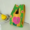 Detail of green and yellow knit tote bag featuring a large pink peach and floral pattern - Tulip Green