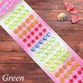 Close-up of assorted colorful crystal gem stickers in heart and star shapes on wood - Shell Series Green