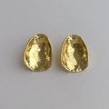 Dettaglio di orecchini ovali dorati con particolare texture metallica martellata e lucida - Grande / Oro Grande