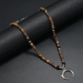 Detail of bohemian crescent moon pendant necklace with dark wood beads on a display stand - Coconut Shell Style