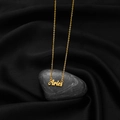Close-up of golden Aries pendant with vintage cursive font on black silk background - Aries Gold