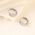 Detalle de pendientes de aro geométricos plateados con circonitas sobre fondo blanco - Plata (Engaste de Corona)