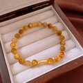Detailed view of beaded bracelet with golden fish charm on white display cushion - Bracelet-Light Coffee