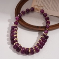 Detail von violetten Acrylperlen mit Marmortexter und goldenen Metall-Abstandshaltern an Kette - Lila