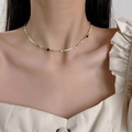 Gros plan de petites perles baroques avec accents dorés et noirs sur un collier ras du cou - Fines perles blanc or noir (30# Collier)