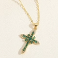 Macro-opname van gouden kruis ketting met groene stenen en witte kristallen details - Smaragd Kruis (Goud)