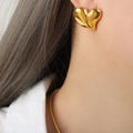 Elegante orecchino a cuore dorato con finitura lucida indossato dalla modella - Orecchini d'oro