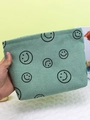 Mint green corduroy makeup bag with black smiley face pattern being held by hand - Green Smiley Face