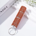 Close-up of sparkling orange rhinestone 3-tier pill box keychain on a decorative background - Orange Red