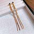 Détail de boucles d'oreilles à pompons dorés avec clous triangulaires noirs sur plateau - Frange Triangle Noir Dorée (Tige en Argent)