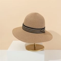 Detalle de sombrero de paja tejido con cinta de rayas blancas y negras en soporte - M (56-58cm) / Caqui