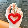 Portachiavi a cuore rosso con strass, anello dorato e moschettone tenuto in mano - Rosso