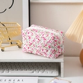 Floral quilted toiletry bag with red flower patterns and white zipper on a desk - Red Flowers Green Leaves