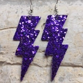 Close-up of sparkling purple lightning bolt earrings with glitter finish and metal hooks - Glitter Purple