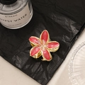 Bohemian gold flower hair claw with pink marble petals on a textured dark surface - Red