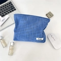 Flat lay detail of blue checkered cosmetic bag with woven label on a white desk - Dark Blue Plaid