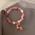 Detailed macro view of a pink strawberry crystal bracelet with gold accents on velvet - Pink Bracelet (30#)