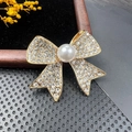 Broche nœud dorée avec cristaux blancs et perle centrale sur fond de velours noir - BZ062 Nœud Pavé
