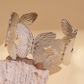 Detailed close-up of a silver hollowed butterfly cuff bracelet on a natural stone - Silver