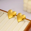 Detailopname van gouden hartknopjes gepresenteerd in een luxe beige fluwelen juwelendoos - Gouden oorbellen