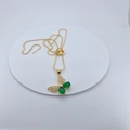 Detail van gouden vlinderhanger met groene peervormige stenen en kleine witte zirkoon - Ketting met Hanger / Groene Vlinder