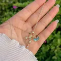 Dettaglio di pendenti a sirena e pietra marina placcati oro 18K su catena a croce - Stile Sirena e Gemma Blu