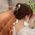 Elegant gold metal hair claw with white enamel flower and green leaves on a bun hairstyle - White Gardenia Claw Clip