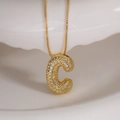 Gold plated initial C pendant necklace with zircon inlay on a white ceramic plate - Letter C (Box Chain)