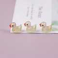 Detailed macro of three mini glowing resin ducks with gold glitter inside and orange beaks - Yellow