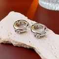 Detail of silver hoop earrings with B-letter charm on a natural stone surface - Letter B Hoop / Silver