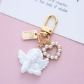 Detail of a vintage golden keychain with baroque angel, pearl heart, and engraved metal tag - Heart Angel with Tag