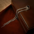 Dettaglio di ear cuff a C argento con catene pendenti su scatola di pelle e libro d'epoca - Ear Cuff con Nappa Argentata