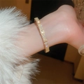Dettaglio macro di un bracciale a quadrifoglio dorato con zirconi indossato al polso - Oro