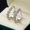 Elegant silver daisy hoop earrings with gold accents displayed in a green velvet box - White Gold