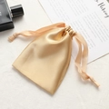 Elegant gold satin drawstring pouch for jewelry storage on a white textured background - Gold