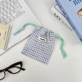 Detailed view of blue checkered drawstring storage bag for makeup and small accessories - White Grid